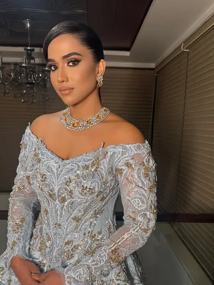 The full view of this elegant low bun shows how it complements a heavily embroidered gown, creating a sophisticated and polished look for a reception or gala.