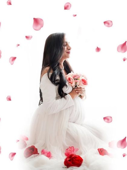 An ethereal portrait of a mom-to-be in a white gown, surrounded by a shower of pink petals. We use creative editing techniques to add a touch of magic and romance to your photos.