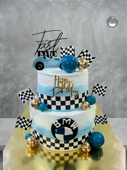 For the ultimate speed lover, I designed this two-tier BMW-themed birthday cake. It features a blue and white ombre design, checkered racing flags, and the iconic BMW logo, making it a perfect centerpiece for a car-themed party.