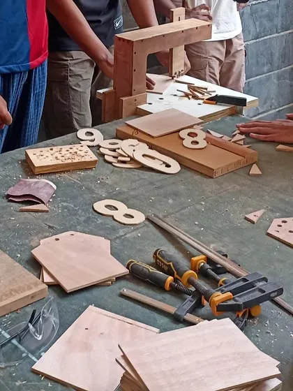 The making of a scoreboard for house points. Students are cutting out numbers from Russian Birch Plywood to be mounted on a stained backboard.