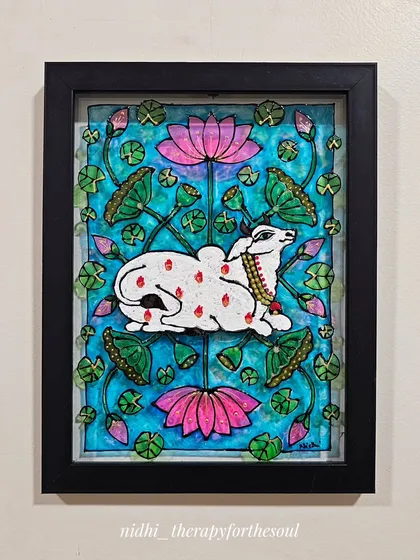 This piece is from "The Moo Project," where I explored my love for cows through different folk art styles. Here, a serene Pichwai cow rests among lotus flowers, painted on a glass base to create a beautiful, luminous effect.