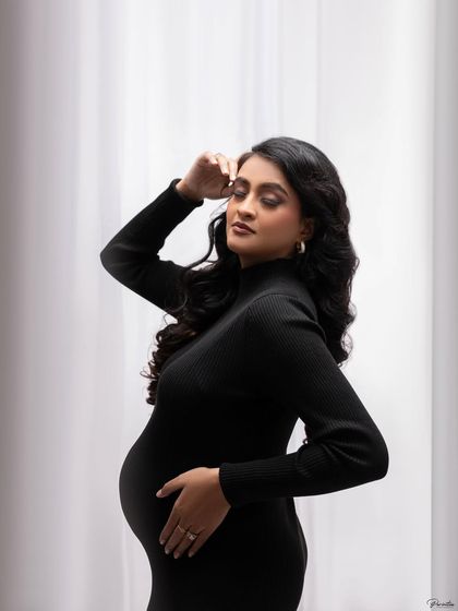 Another artistic shot with the black dress against a simple white curtain, playing with light and shadow for a moody and modern portrait.