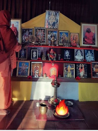 A swami preparing the altar, which is adorned with images of the gurus and deities of our lineage. The altar is the focal point for our daily prayers and ceremonies.