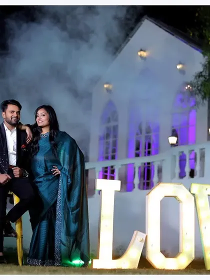 Our stunning white chapel backdrop creates a magical, romantic setting for pre-wedding photoshoots, especially during the evening. We use dramatic lighting and props like these illuminated 'LOVE' letters to make your couple portraits truly unforgettable.