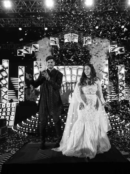 Another angle of the couple's grand Sangeet entry, captured in a classic black and white photo that emphasizes the emotion and the spectacle of the confetti shower.