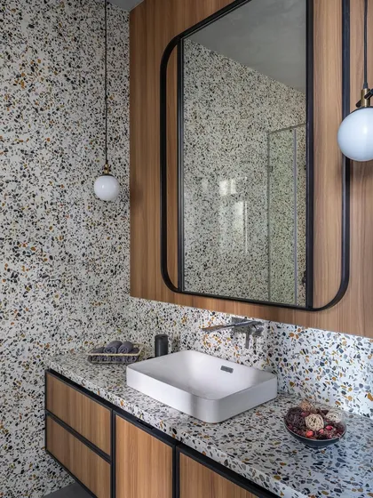 We love the playful yet sophisticated look of terrazzo. In this guest bathroom, we used terrazzo on both the countertop and the wall, pairing it with warm veneer cabinetry for a modern and textural feel.