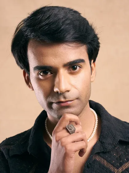 A retro-inspired look. The grooming is clean and classic, with a side-parted hairstyle that gives a nod to a bygone era.