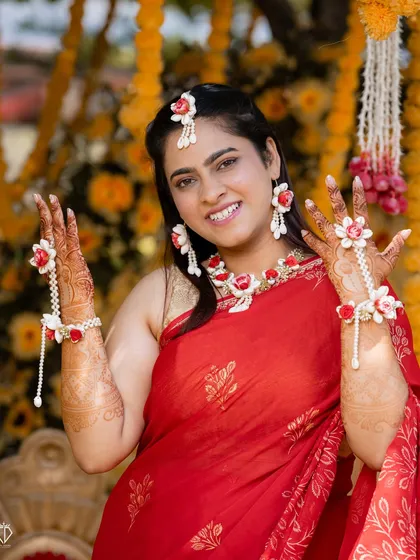 The bride showing off her beautiful floral jewelry and henna-stained hands during her Haldi ceremony.