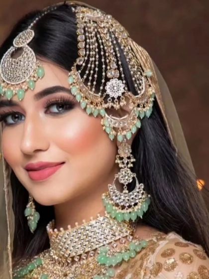 A smiling model wearing a mint green beaded set with a diamond-like finish. This is a beautiful fusion of traditional colors and modern sparkle.