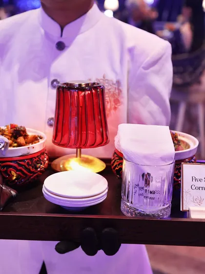 'Five Spice Baby Corn & Broccoli' served in ornate bowls on a themed tray. This dish is part of our curated Pan-Asian menu, designed for an authentic experience.