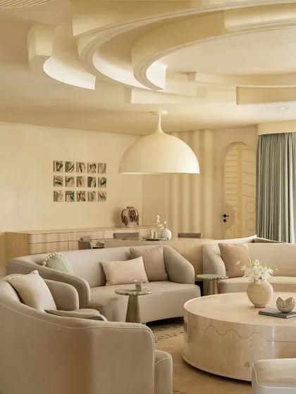 The living space in our 'Soft Serve' project is imagined as a series of intersecting circles. Curvilinear sofas and a sculptural ceiling design create a hypnotic visual of ripples and waves, all in a calming, ecru-toned palette.