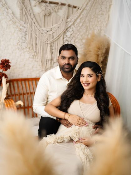 A beautifully framed shot of the couple, with pampas grass in the foreground. This creative composition adds depth and a soft, dreamy quality to the maternity portrait.