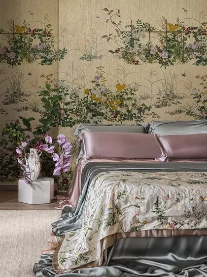 A tranquil bedroom sanctuary enveloped by our Scenic Flora chinoiserie wallpaper. The delicate, hand-painted appearance of Japanese wildflowers creates a romantic and poetic backdrop, perfectly complemented by luxurious silk bedding for a truly immersive experience in elegance.