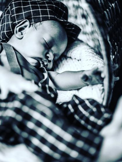 A charming, vintage-style black and white photo of a sleeping newborn in a flat cap. This shows how creative styling can add a unique personality to newborn portraits.