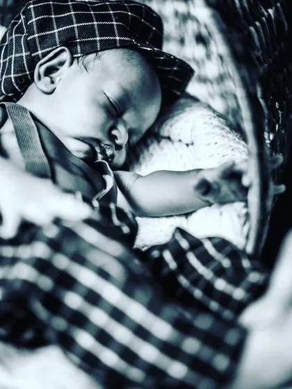 A charming, vintage-style black and white photo of a sleeping newborn in a flat cap. This shows how creative styling can add a unique personality to newborn portraits.