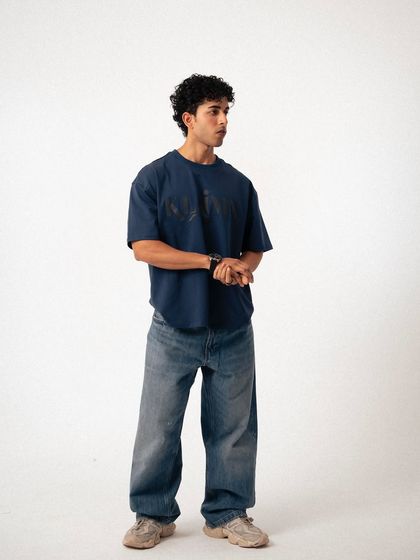 A clean, three-quarter studio shot for a lookbook. This provides a clear and stylish view of the oversized t-shirt and baggy jeans, perfect for e-commerce.