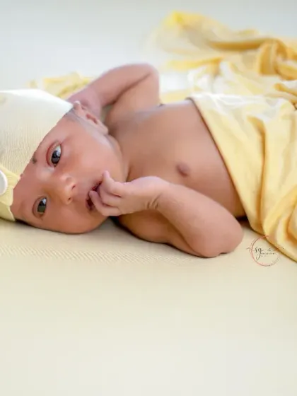Hello, world. This simple, beautiful shot captures a newborn's curious gaze, wrapped in a soft yellow blanket.