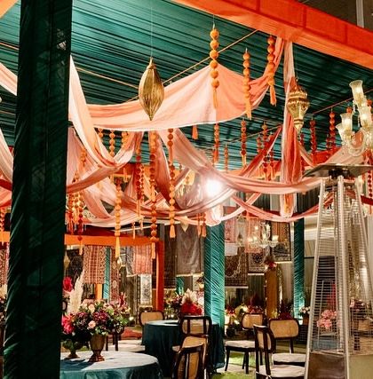 A canopied seating area with draped fabrics, hanging tassels, and elegant chandeliers, creating an intimate and luxurious space for guests.
