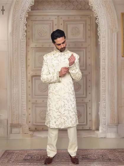 Classic elegance for the modern groom or wedding guest. This off-white sherwani features subtle, intricate embroidery, offering a look of timeless sophistication. We ensure the fit and fall is perfect, so you look sharp and feel comfortable.