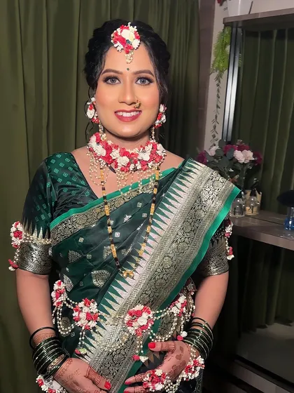 A beautiful look for a baby shower (dohale jevan). The mom-to-be is glowing in a traditional green saree, adorned with fresh floral jewellery.