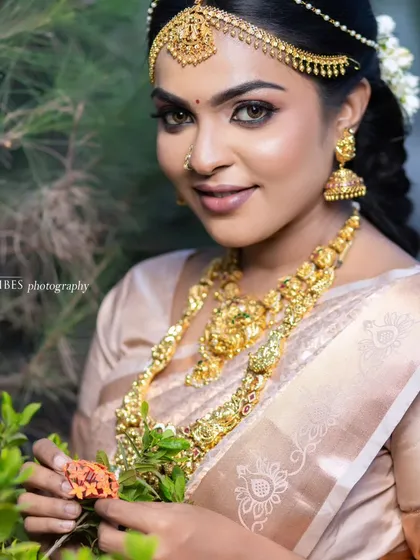 A beautiful outdoor shot of a model in a traditional look. The natural light highlights the dewy finish of the makeup and the intricate jewelry.
