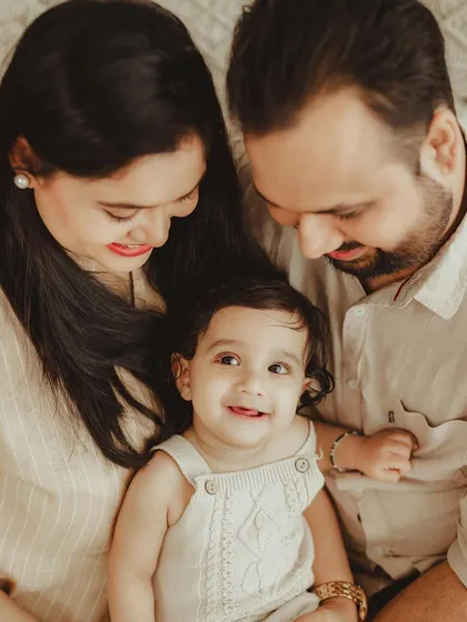 A happy family of three sharing a sweet moment. The warm, earthy tones of their outfits and the setting create a cozy and intimate feel.