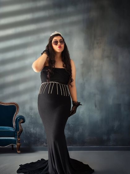 Queen of her castle. This portrait combines glamour and attitude, with a tiara, sunglasses, and a sassy pose against a moody, elegant backdrop.