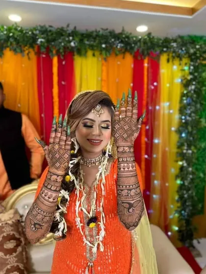 A happy bride showing her back hand mehndi during her ceremony. The design features a mix of net patterns and bold paisley motifs, creating a stunning visual effect.
