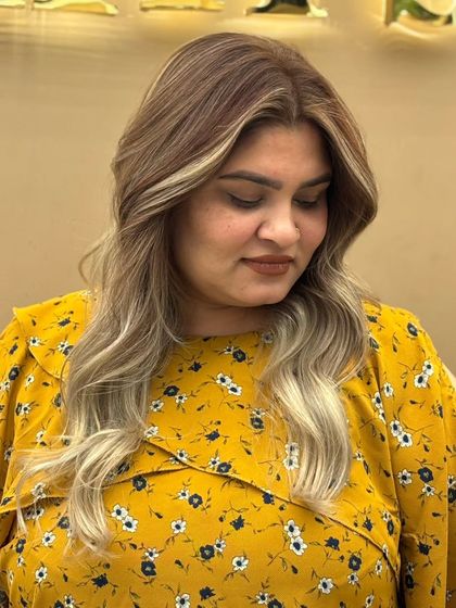 A client showcasing her dramatic blonde ombré. The contrast between the dark roots and light ends is bold and beautiful, perfect for a statement look.