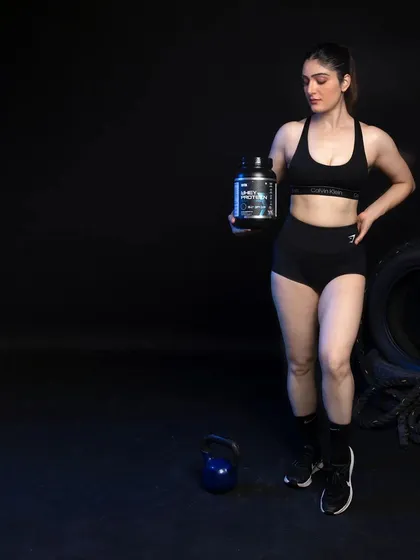 A three-quarter shot of the female model holding the whey protein. The use of negative space on the left makes this image versatile for use in web design or ad copy where text needs to be added.