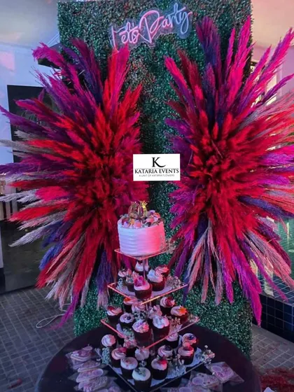 Creating fun photo spots is one of my favorite things to do. For this party, I designed a backdrop with a "Let's Party" neon sign and dramatic pampas grass wings against a lush green wall, perfect for birthday or anniversary photos.