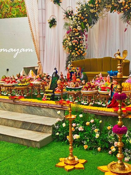 A beautiful baby shower setup on a raised stage, with a floral arch and a full display of traditional plates.
