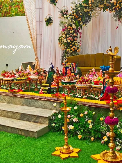An elegant baby shower setup on a raised platform, with lush greenery and beautiful floral arrangements.