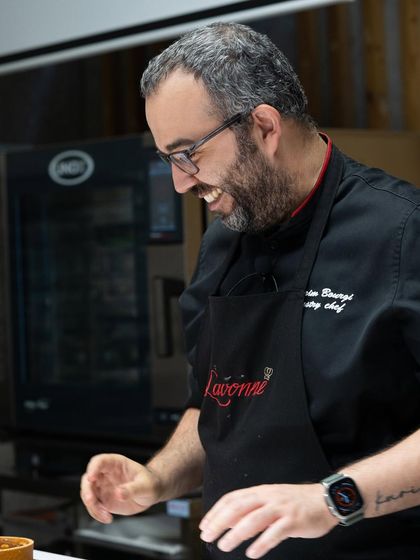 The joy of creation. A guest chef smiles as he works, his passion for pastry evident in every movement.