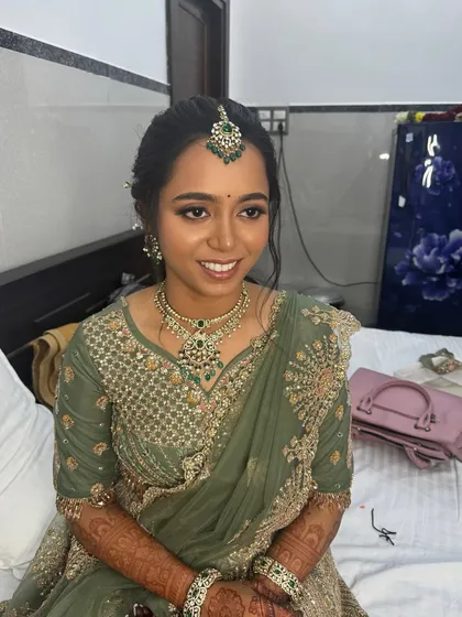 A smiling portrait of Anitha, looking happy and confident in her reception makeover. The soft glam look is perfect for her elegant green saree.