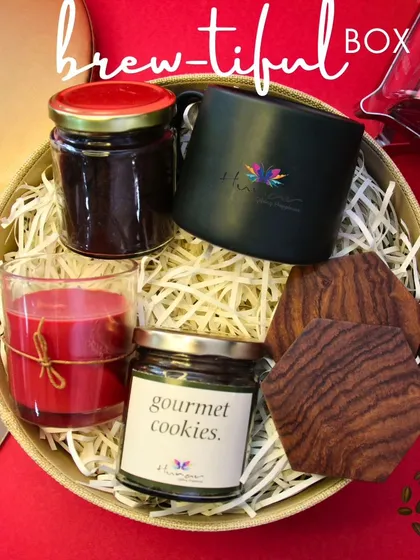 Our "Brew-tiful Box" is the perfect gift for any coffee aficionado. This curated hamper includes gourmet coffee, a custom-branded mug, artisanal cookies, elegant wooden coasters, and a scented candle to create a complete sensory experience.
