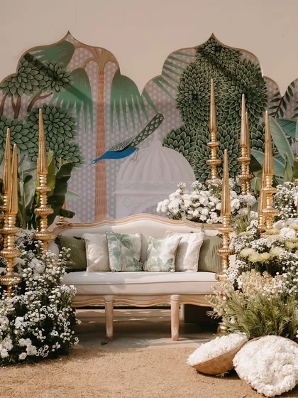 The full view of the personalized photo corner, with a comfortable sofa set against a stunning hand-painted mural depicting peacocks and palaces.