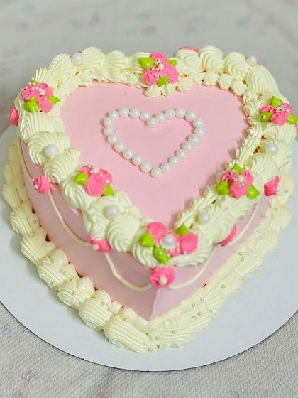 A beautiful pink heart-shaped anniversary cake with delicate piping.