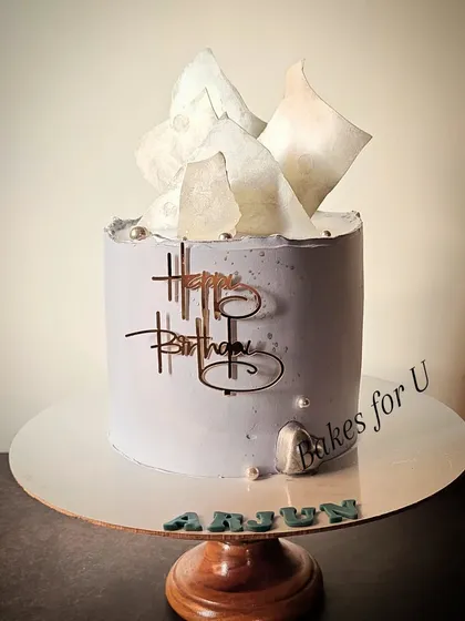 A sophisticated cake for a man, in a cool grey tone with abstract wafer paper sails on top. The clean lines and minimalist design make it a modern and stylish choice.