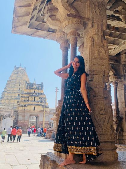 A traveler posing elegantly by a pillar at the Virupaksha Temple in Hampi.