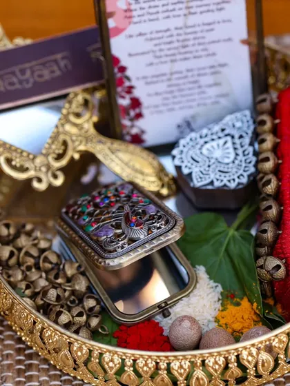 A tray of traditional welcome items, beautifully arranged with ghungroos, a decorative mirror, and kumkum. I ensure that even the smallest ritualistic elements are presented with artistic flair.