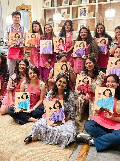 A large group photo from a cafe workshop, showcasing the variety of beautiful paintings created. It's a testament to everyone's creativity.