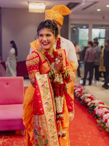 The bride's happy entrance, surrounded by family. Her orange and red nauvari saree is vibrant and traditional.