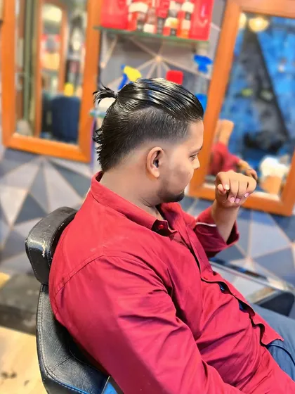 From the back, you can see how the longer hair is gathered into a small ponytail, while the sides are kept short and clean with a fade.