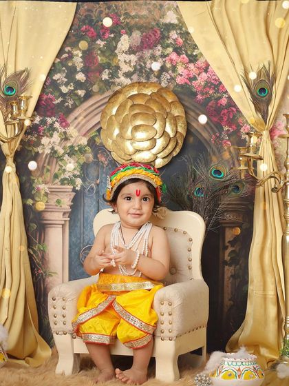 A calm and composed little Krishna sitting gracefully on his chair. This portrait highlights the beautiful details of the costume and the elegant studio set.