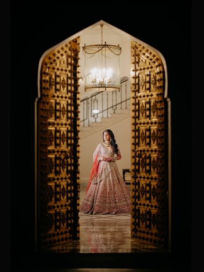 A grand bridal portrait of Chitranksha framed by an ornate golden doorway. This shot emphasizes the royalty and scale of her Jaipur wedding, making her look like a queen in her palace.