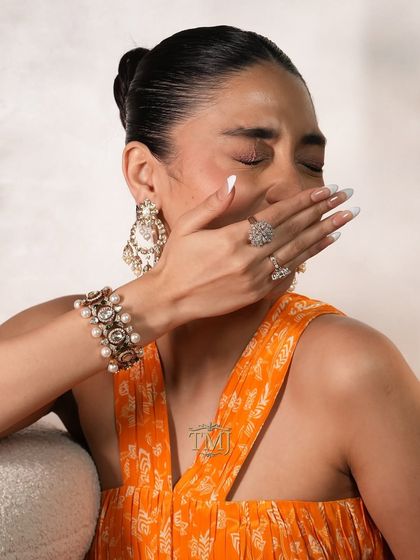 A candid shot of a model wearing our convertible polki and pearl bracelet, paired with matching pearl chandbalis and diamond rings.