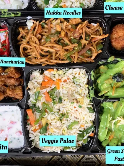 An Indo Chinese fusion meal tray for a change of pace. This box contains Green Sauce Pasta, Veg Hakka Noodles, Veggie Pulao, Babycorn Manchurian, a cheese ball, and raita.
