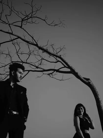 A striking black and white portrait. The composition, with the bare tree branches above them, creates a strong, graphic image that is both artistic and emotional.