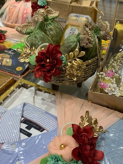 This trousseau display includes a mix of gifts for the bride and groom, from a basket of Ferrero Rocher to elegantly packed shirts, all decorated with rich red and gold floral details.